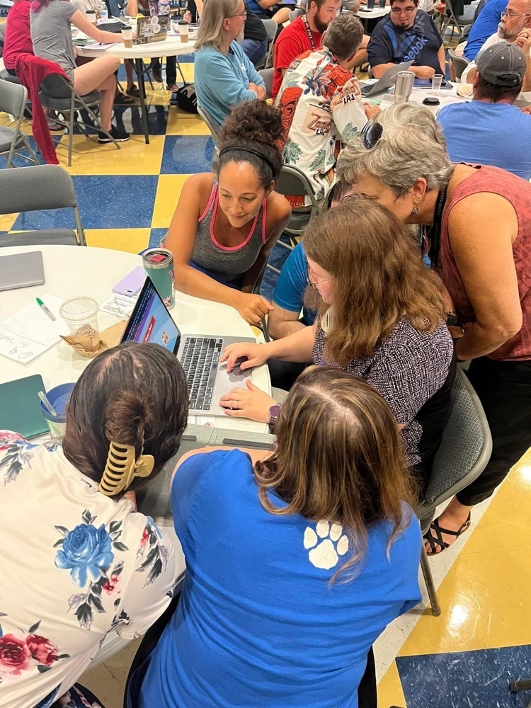 teachers gather around a computer 